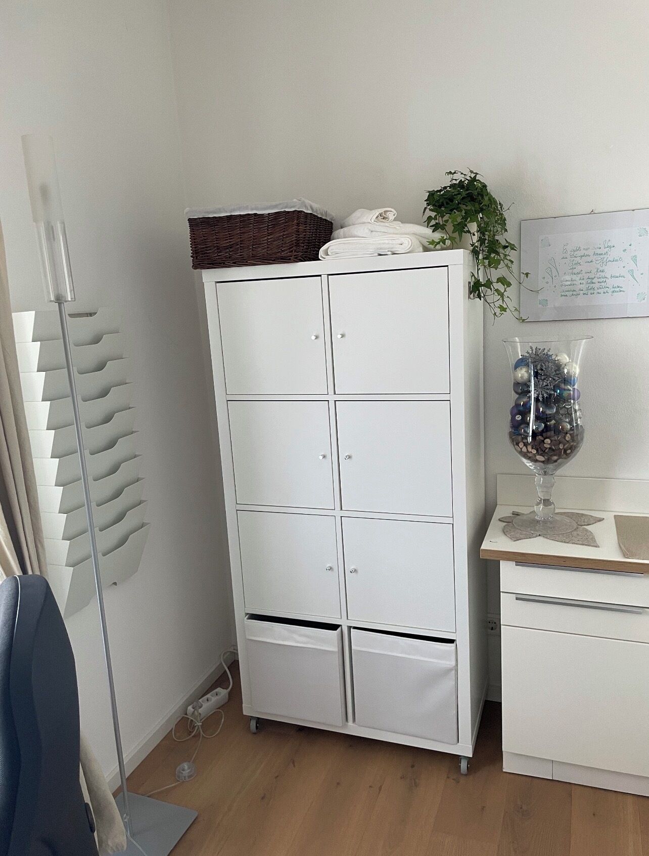 A white wardrobe with multiple drawers and a basket on top.