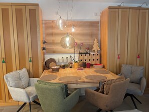 Un coin repas comprenant une table en bois, quatre chaises, un luminaire suspendu et un meuble fixé au mur.