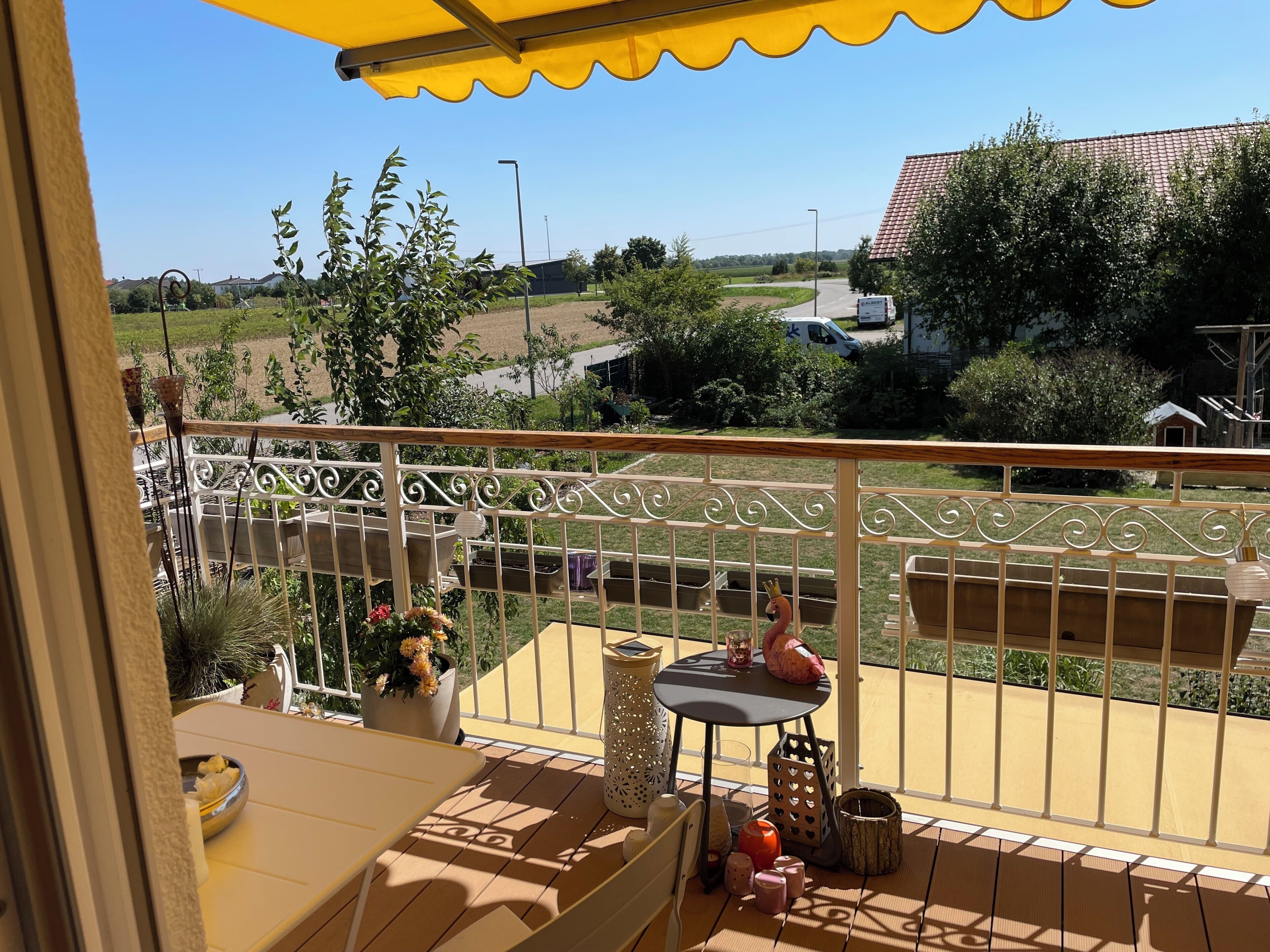 Ein Balkon mit Blick auf eine ländliche Landschaft, ein Tisch mit dekorativen Gegenständen und ein Metallgeländer.