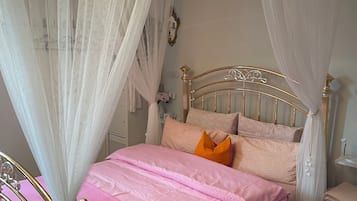 Un lit à baldaquin, une table de chevet et un miroir fixé au mur.