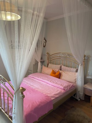 Una cama con dosel, una mesita de noche y un espejo instalado en la pared.