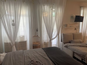 A bedroom with two beds, a television, a clock, and sheer curtains. - Résidence Blanc Suites - Private Ferienresidenz mit Pool & Garten - nahe Flughafen Straubing - Wallmühle (Rain)