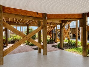 A wooden structure with a concrete floor, surrounded by plants and a brick pathway. - Turtle Cottage: 3BR 2BA, Oceanfront, Rooftop Deck, Gazebo, Sleeps 7 (Oak Island)