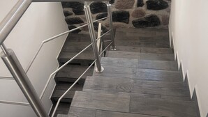 Un escalier avec une rampe métallique menant à un mur de pierre.