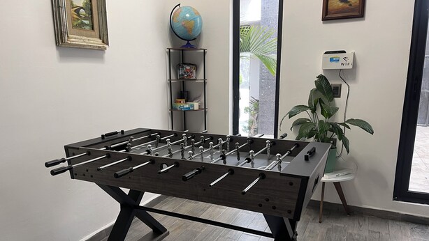 Une table de baby-foot dans une pièce avec une fenêtre, un globe terrestre et un routeur Wi-Fi.