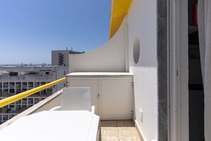 A balcony with a white table, a yellow railing, and a view of the sea. - #415 Charming Apartment | Albufeira (Albufeira)