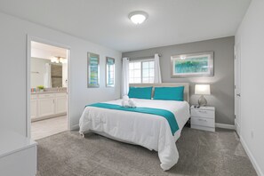 A bedroom with a bed, a nightstand, a lamp, a window with curtains, and a bathroom visible through an open door. - Spacious Family Retreat w/ Pvt Pool + BBQ at Champions Gate (Davenport)