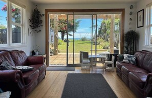 Ein Wohnzimmer mit einer Schiebetür, die auf eine Terrasse mit Meerblick führt.