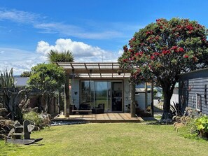 Una casa moderna con puerta de cristal, un porche cubierto y un jardín cuidado.