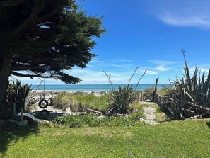 A beach pathway leading to the ocean with a clear sky.