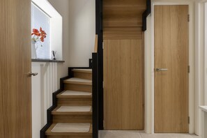 A staircase with wooden steps and black edges, leading to a door with a handle. - The Old Abattoir -  an apartment that sleeps 2 guests  in 1 bedroom (Chipping Campden)