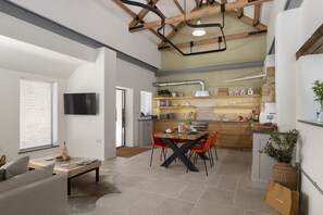 A modern kitchen with a dining area, wooden beams, and a flat-screen TV. - The Old Abattoir -  an apartment that sleeps 2 guests  in 1 bedroom (Chipping Campden)