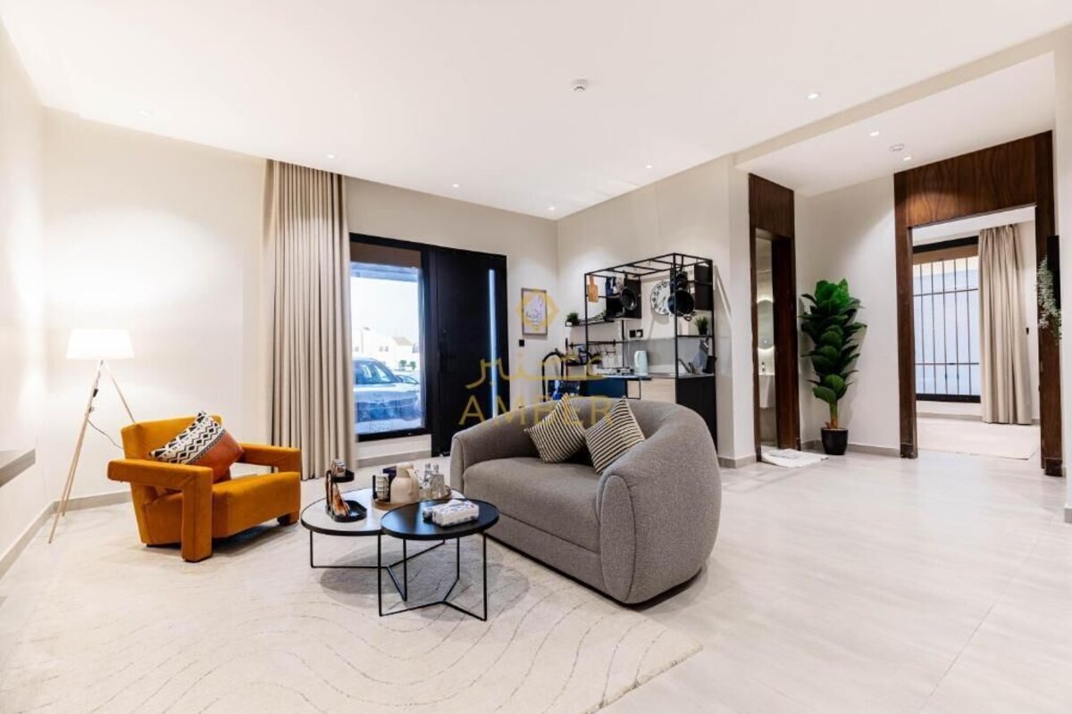 Ein modernes Wohnzimmer mit Sofa, Sessel, Couchtisch und Bücherregal.
