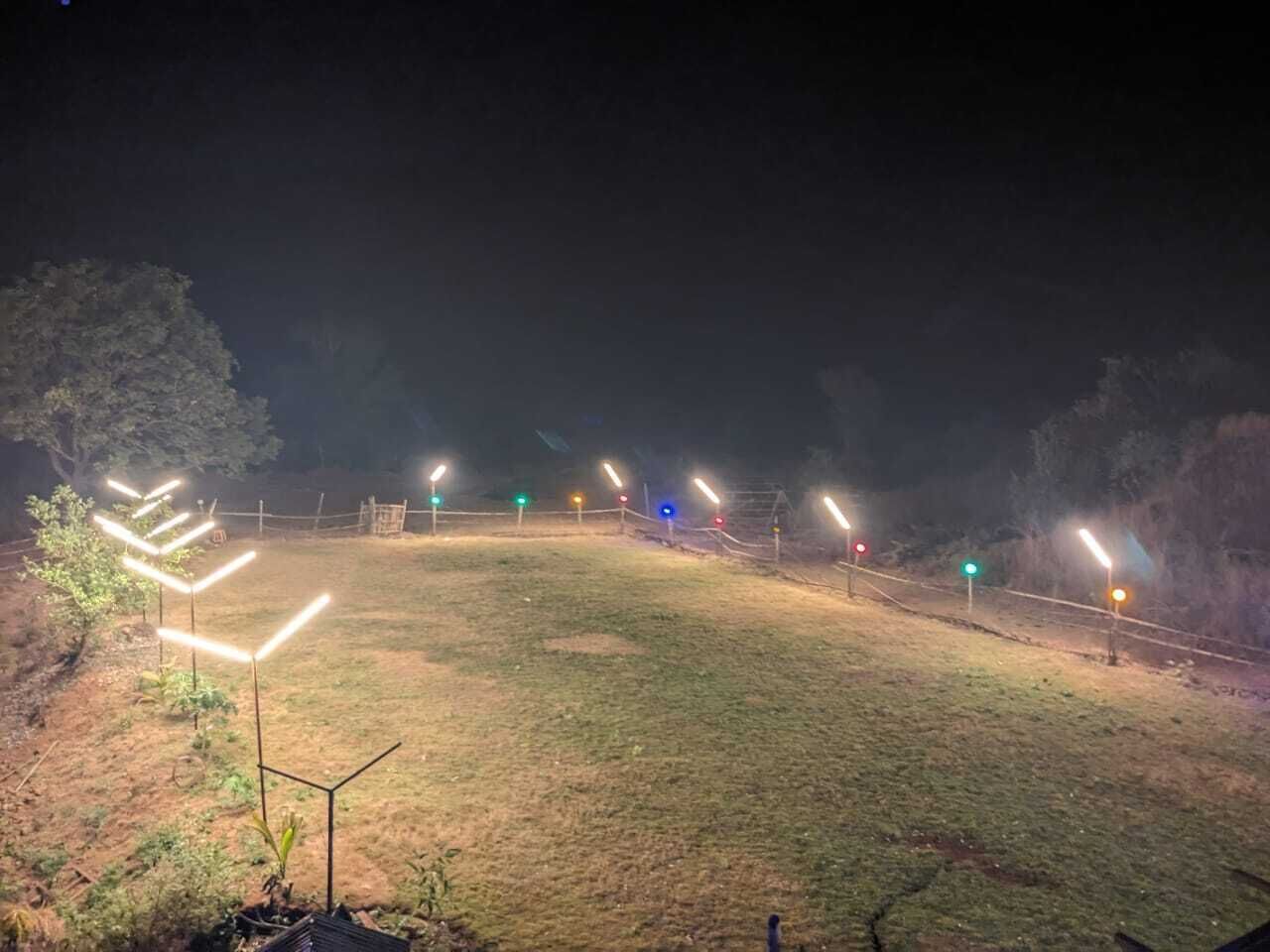 A grassy outdoor area with multiple light poles and a fence.