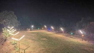 A grassy outdoor area with multiple light poles and a fence.