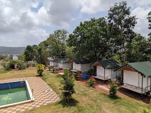 Un camping con varias tiendas de campaña, una piscina y un sendero a cuadros.