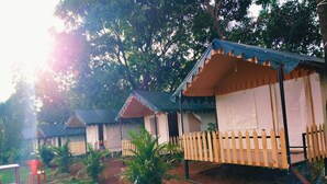 A row of small, single-story cabins with a picket fence in front, surrounded by greenery.