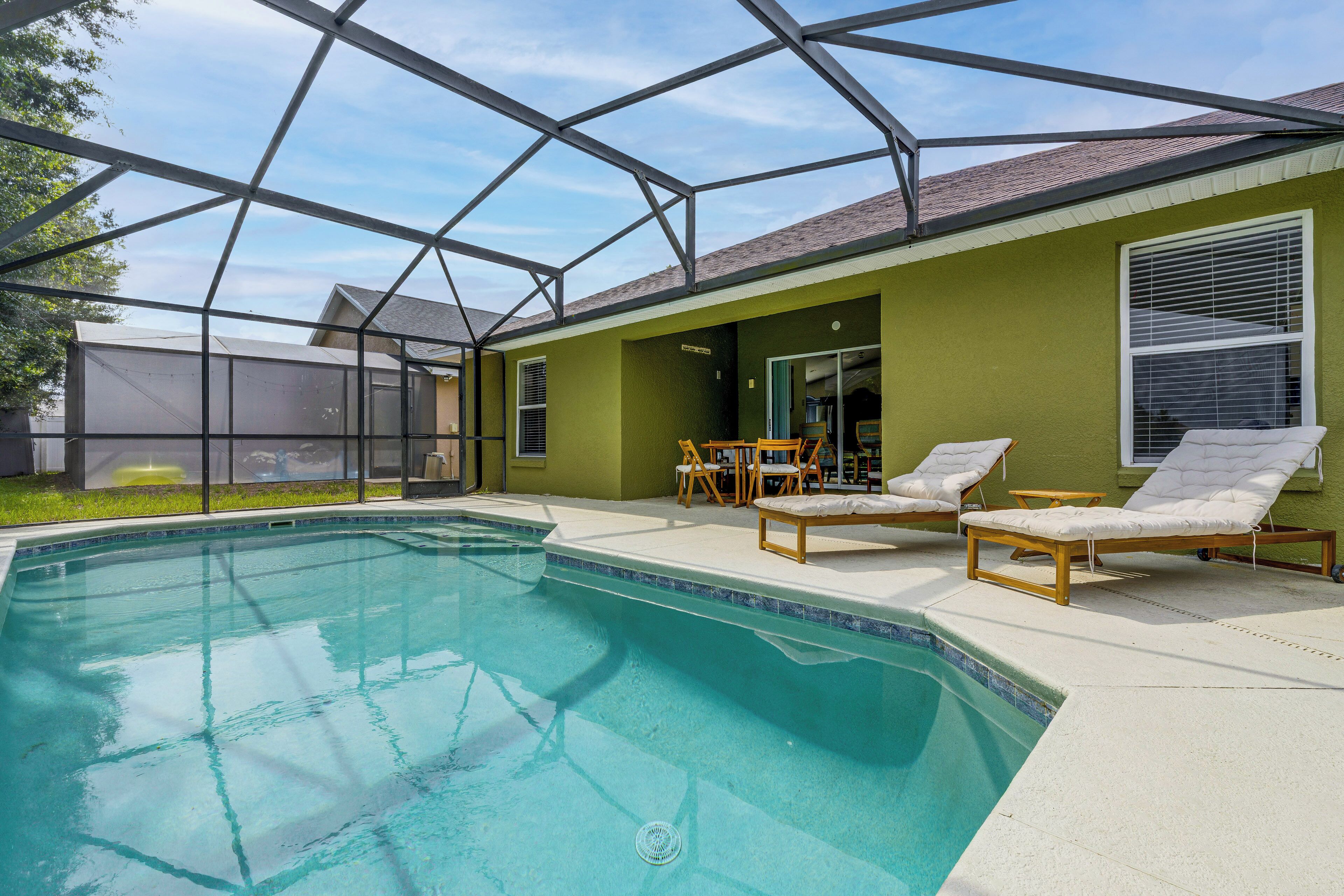 A swimming pool with lounge chairs and a covered patio area.
