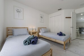 Een slaapkamer met twee eenpersoonsbedden, een houten nachtkastje met een lamp en een kledingkast.