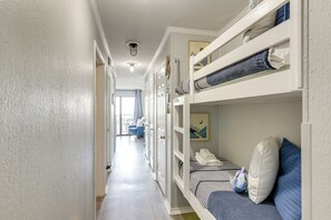 A narrow hallway with bunk beds, a door, and a window leading to a balcony. - Poolside Vibes, Beach Strolls! Galveston Getaway (Galveston)