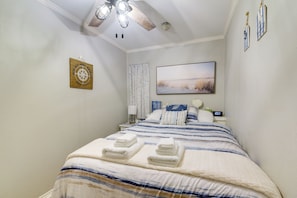 Ein Schlafzimmer mit einem Bett, einem Deckenventilator, einem Gemälde, einer Uhr und einer Wanddekoration.