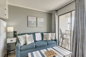 Ein modernes Wohnzimmer mit Sofa, Couchtisch und Blick ins Freie durch ein großes Fenster.
