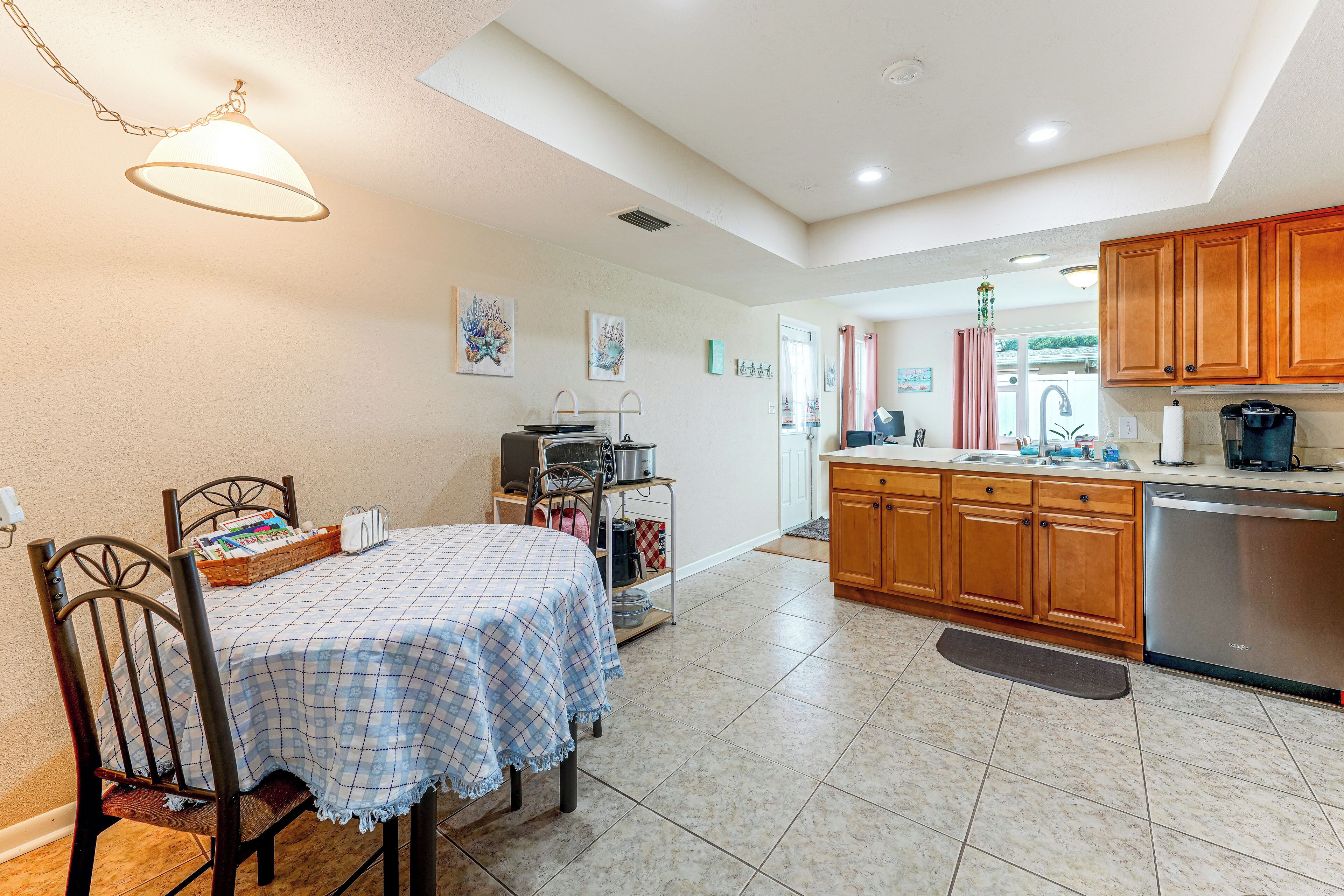 A kitchen with wooden cabinets, a dining table with chairs, and a kitchenette area.