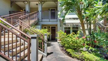 A multi-level building with a central staircase, outdoor plants, and a covered walkway.