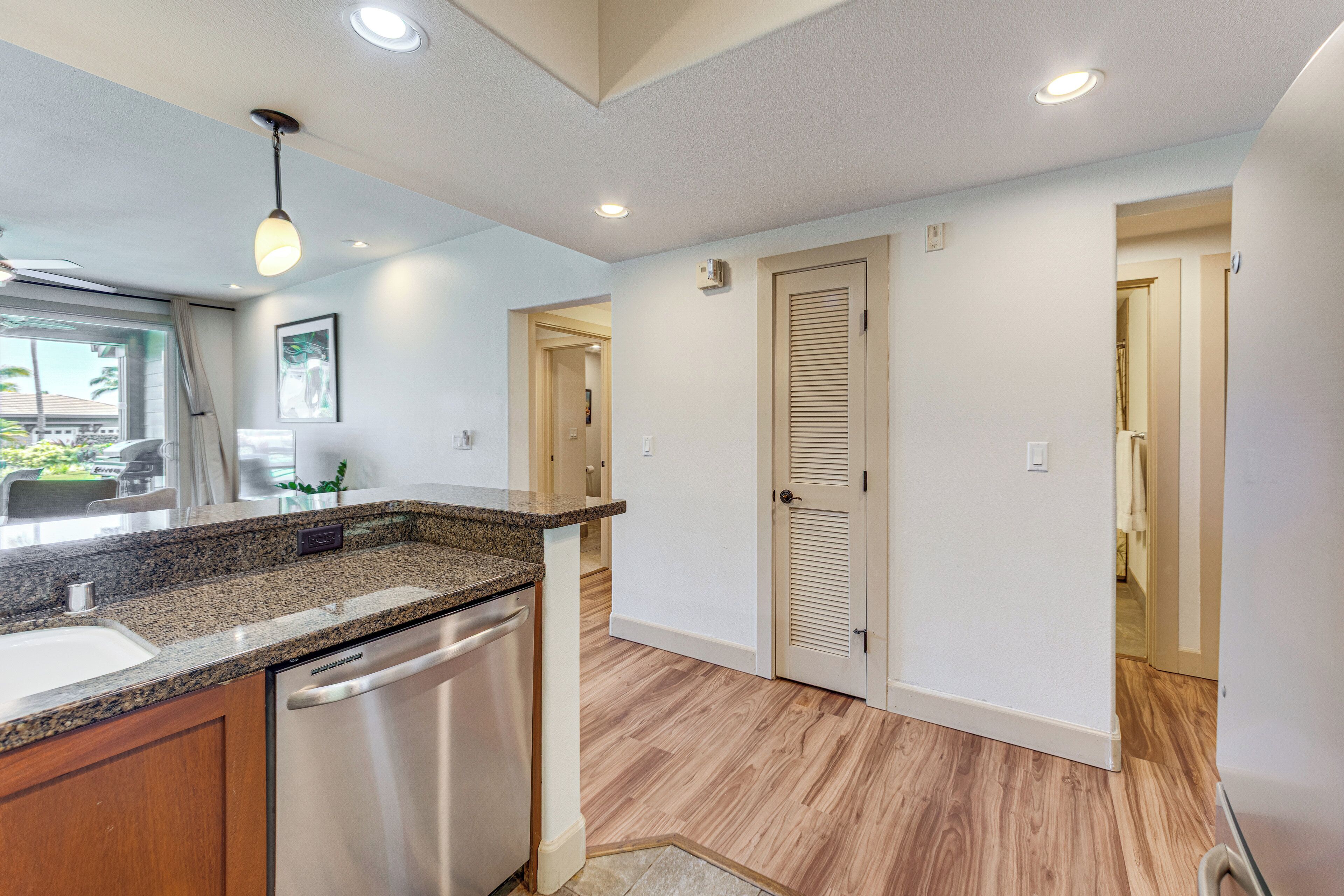 A modern kitchen with granite countertops, stainless steel appliances, and wooden flooring.