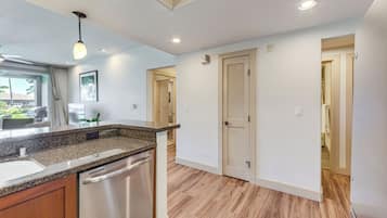 A modern kitchen with granite countertops, stainless steel appliances, and wooden flooring.