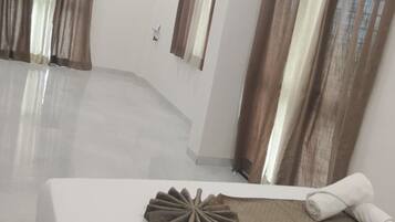 A hotel room with a large bed, a ceiling fan, and curtains on the windows.