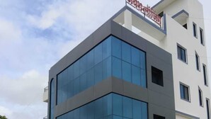A multi-story building with a modern architectural design, featuring large glass windows and a flat roof. - Jayesh Lodging (Shirur)