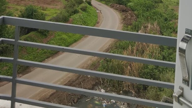 A rural landscape with a winding road, greenery, and a clear sky. - Jayesh Lodging (Shirur)