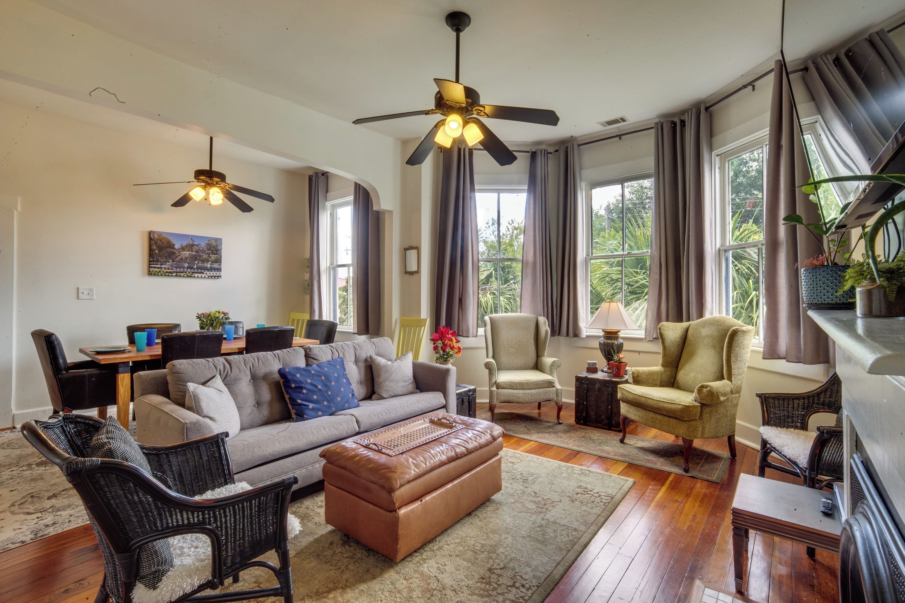 A living room with a sofa, chairs, a coffee table, a fireplace, and a ceiling fan.
