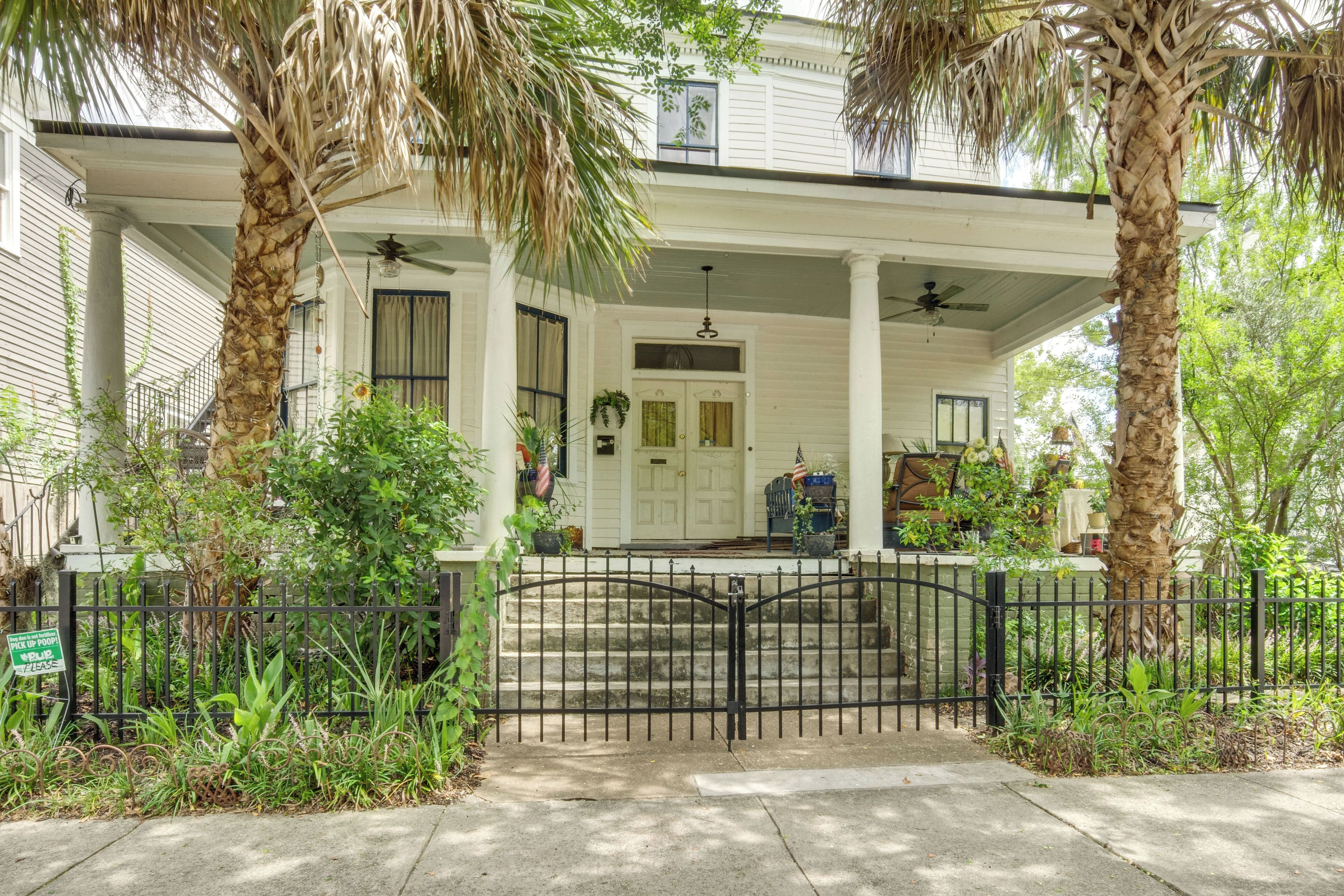 A two-story house with a porch, a black iron fence, and a front door.