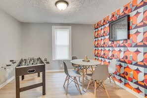 A room with a foosball table, a round dining table with chairs, and a colorful geometric wall mural. - Walk to University of Akron! Game Day Getaway (Akron)