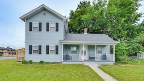 A two-story house with a front porch, a chimney, and a small garden.
