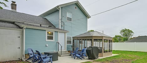 A house with a covered patio area, outdoor seating, and a garage.