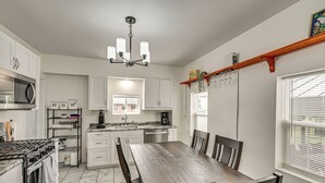 A modern kitchen with white cabinets, a granite countertop, a built-in oven, and a dining area with a wooden table and chairs.