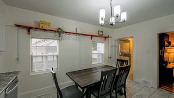 Un comedor con una mesa y sillas de madera, un lámpara en el techo y una ventana con persianas.