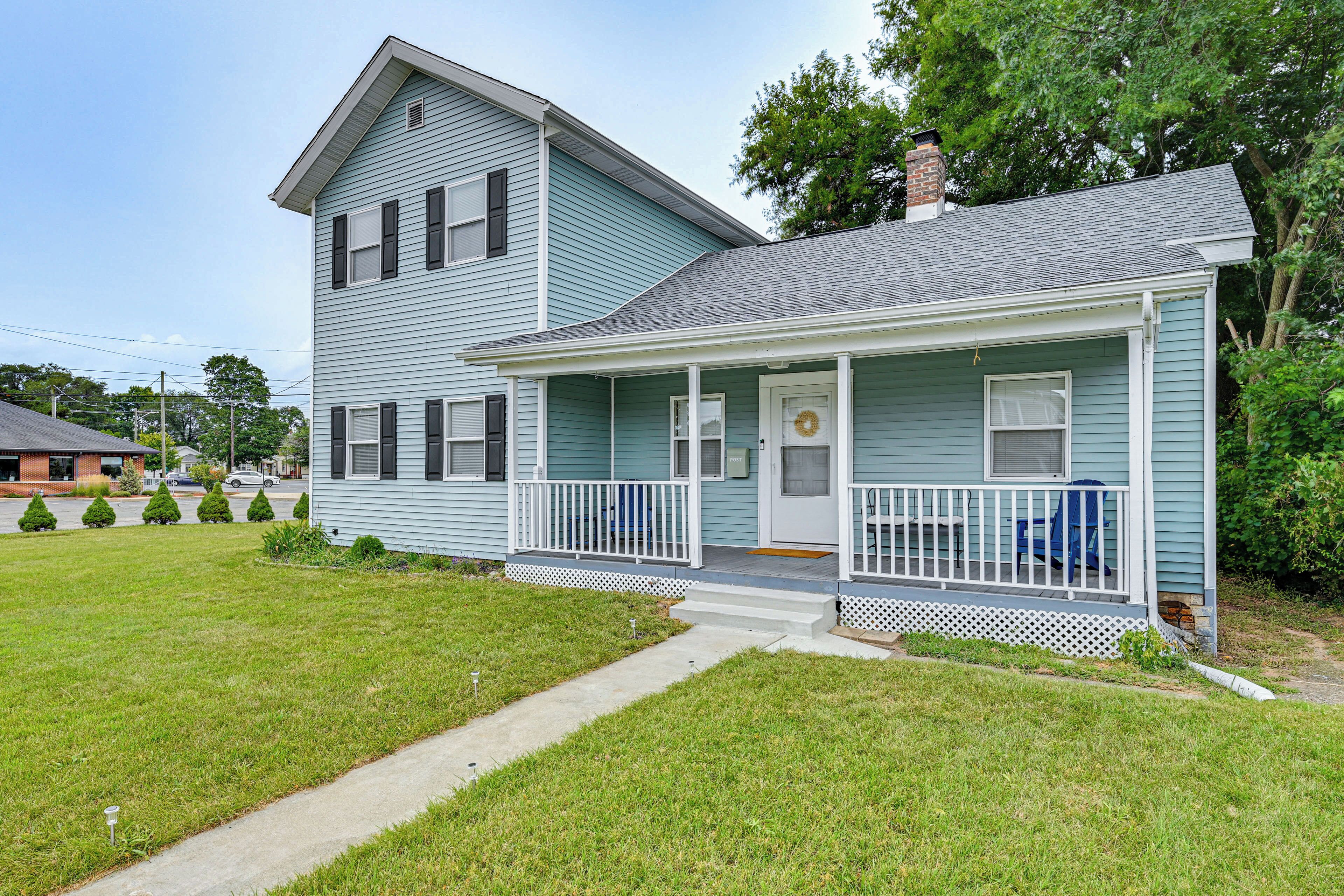 A two-story house with a porch, a chimney, and a mailbox.