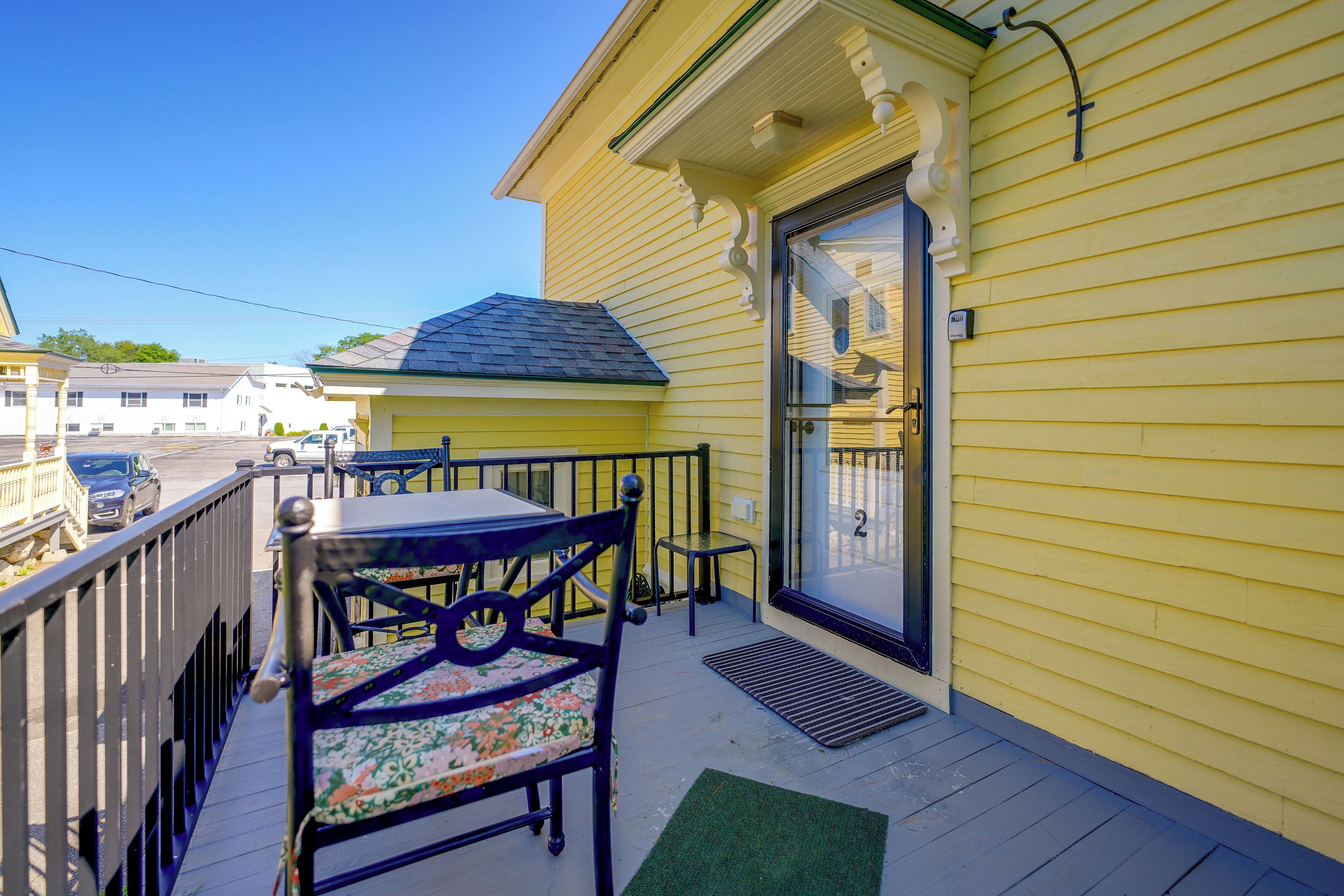 A yellow house with a porch, a table, and two chairs.