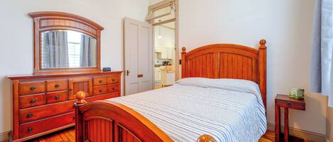 A bedroom with a wooden bed, a dresser, a mirror, and a ceiling fan.