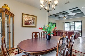 A dining room with a round table, chairs, a chandelier, a framed painting, and a potted plant. - 6 Mi to Port Charlotte Beach Park! Family Getaway (Port Charlotte)