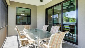 A covered patio with a glass door leading to a balcony, a ceiling fan, and a table with chairs. - 6 Mi to Port Charlotte Beach Park! Family Getaway (Port Charlotte)