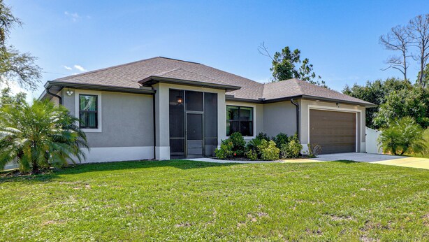 A single-story house with a garage, a front yard, and a clear sky. - 6 Mi to Port Charlotte Beach Park! Family Getaway (Port Charlotte)