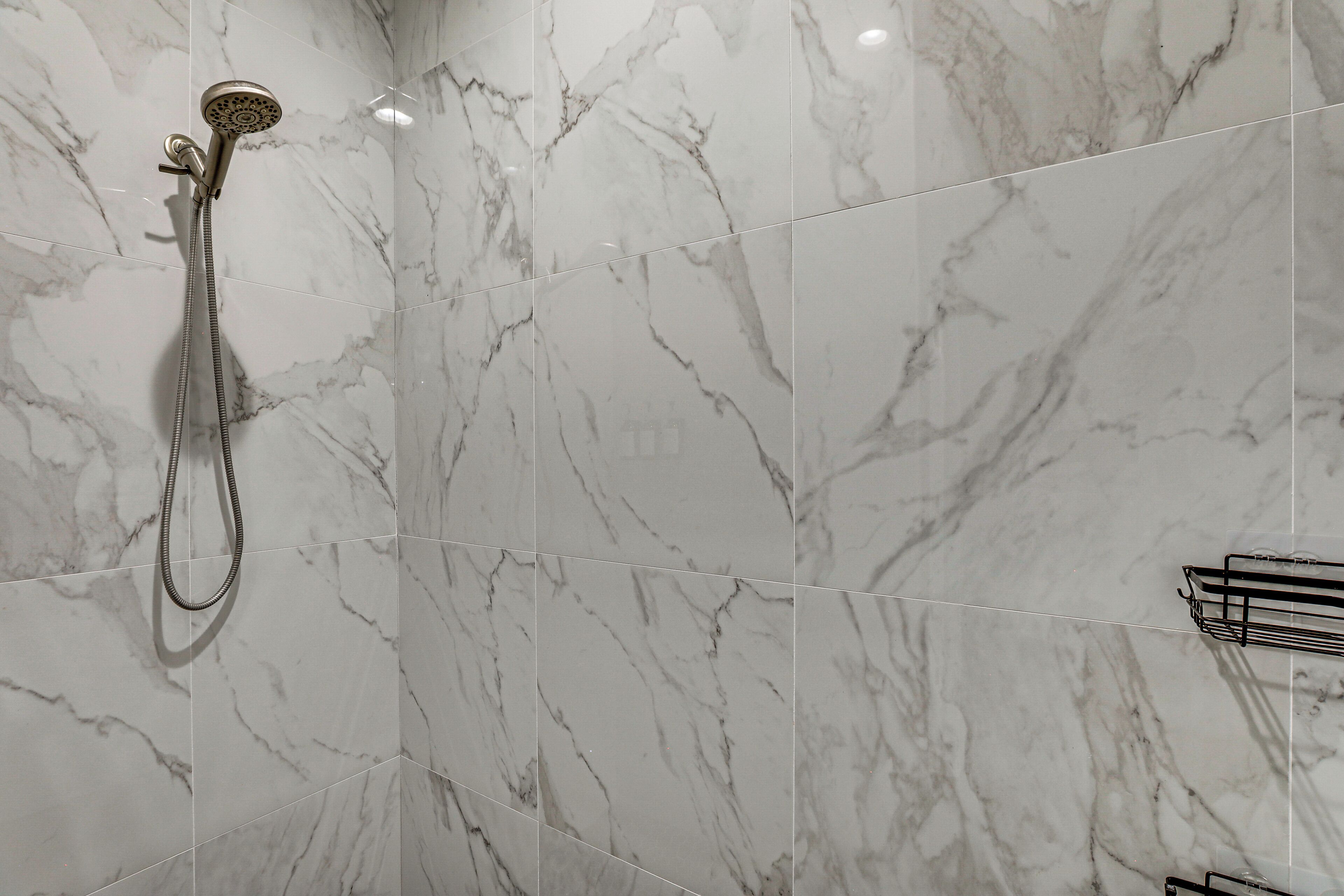 A bathroom with a shower, tiled walls, and a metal rack.