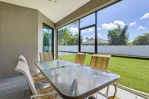 A glass-top table with four chairs, a white fence, and a clear view of the sky and trees. - 6 Mi to Port Charlotte Beach Park! Family Getaway (Port Charlotte)