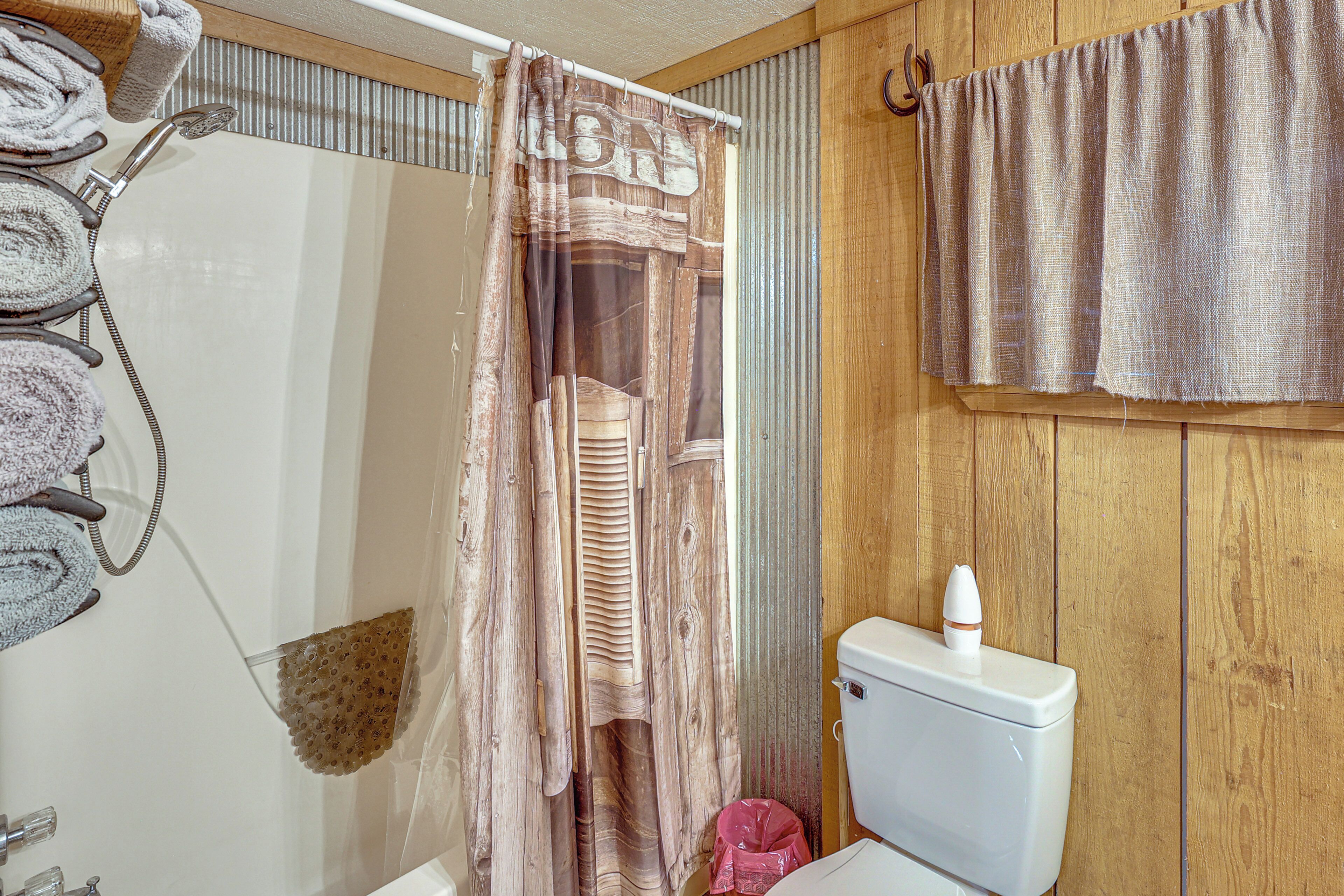 Ein Badezimmer mit Duschvorhang, Toilette und Handtuchhalter.