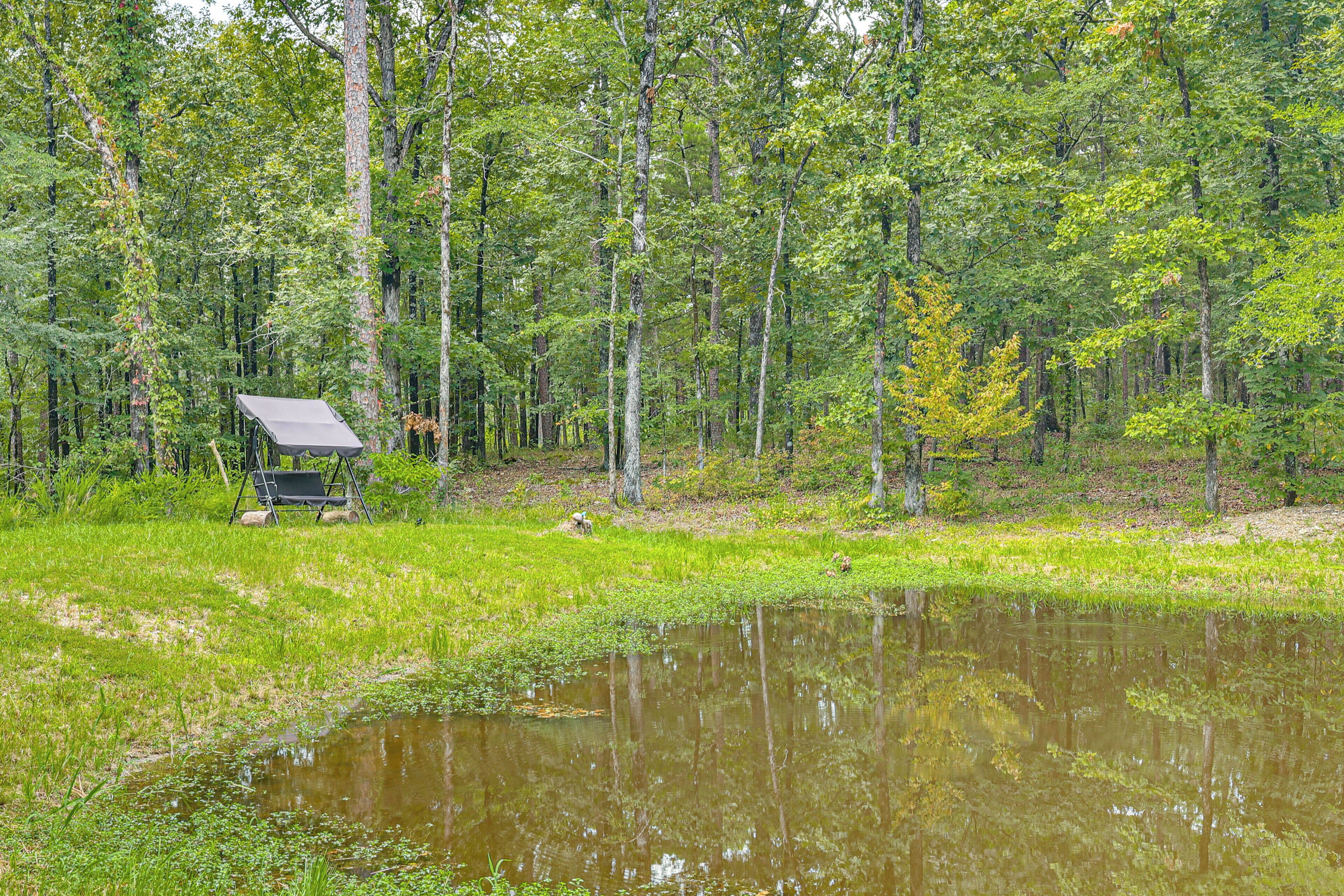 Ein Campingplatz mit Zelt und Picknicktisch in einer bewaldeten Gegend mit Teich.